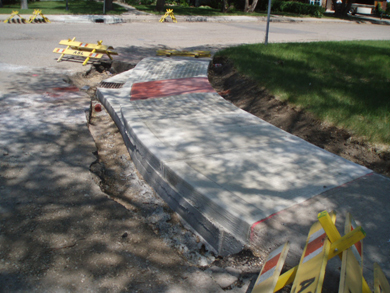 Un nouveau trottoir de béton, à côté d'une section de route non pavée le long de la rue Dorothy