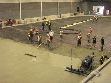 Des ouvriers coulent un nouveau plancher de béton à l'intérieur du complexe