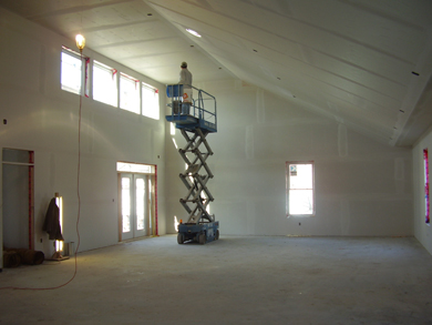 Un travailleur de la construction utilise un chariot élévateur électrique pour installer des plaques de plâtre et pour fixer les murs intérieurs et le plafond.