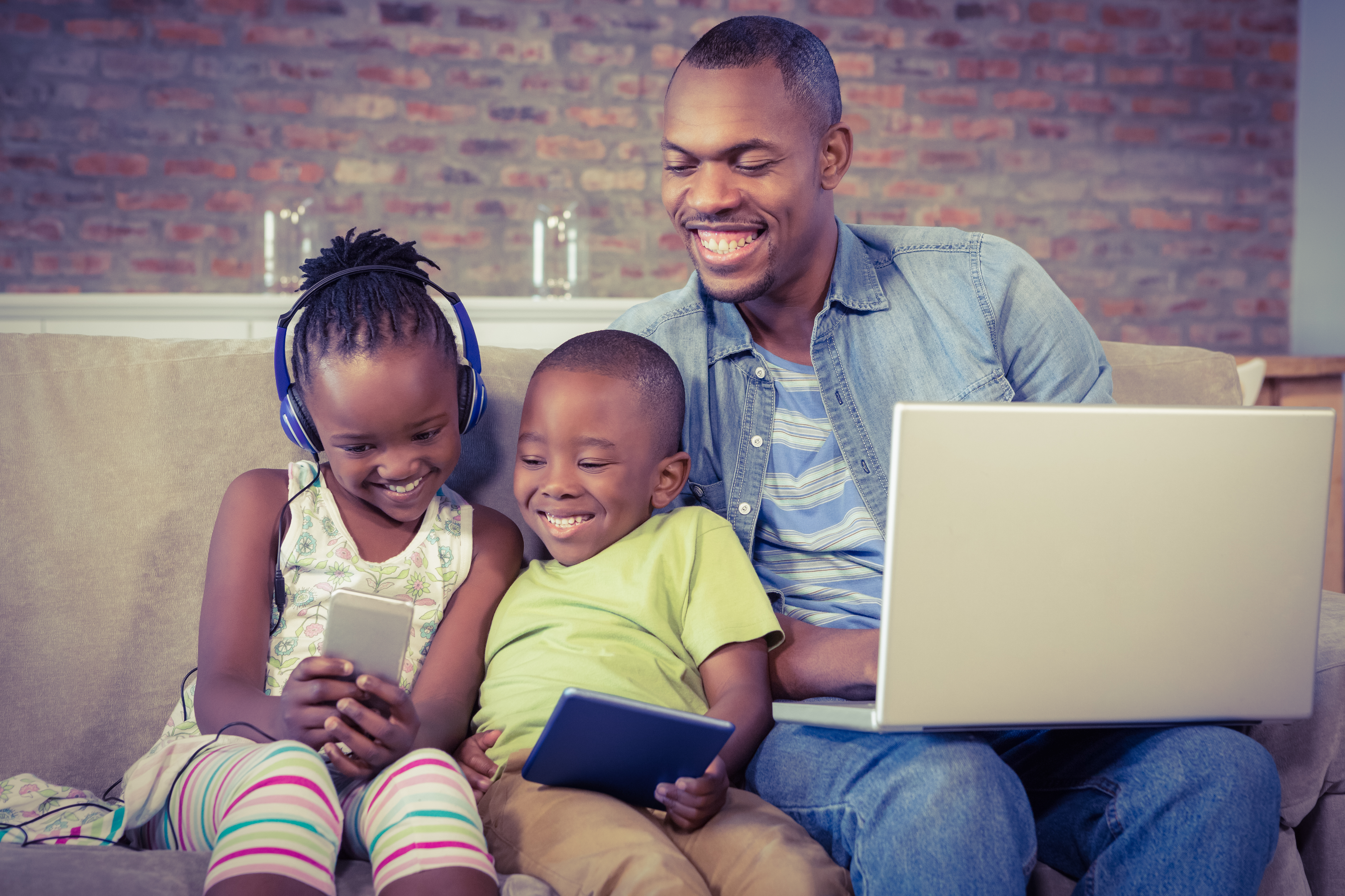 A family using a cell phone, tablet and a laptop